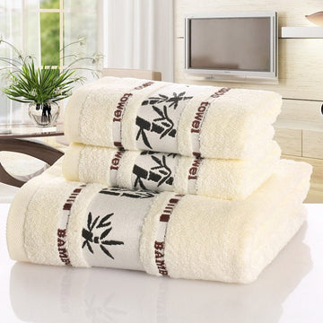 Set of white towels with bamboo style print on a reflective surface, with an interior indoor background.
