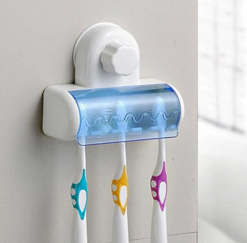 Wall-mounted toothbrush holder with three colorful toothbrushes on a light gray wall.