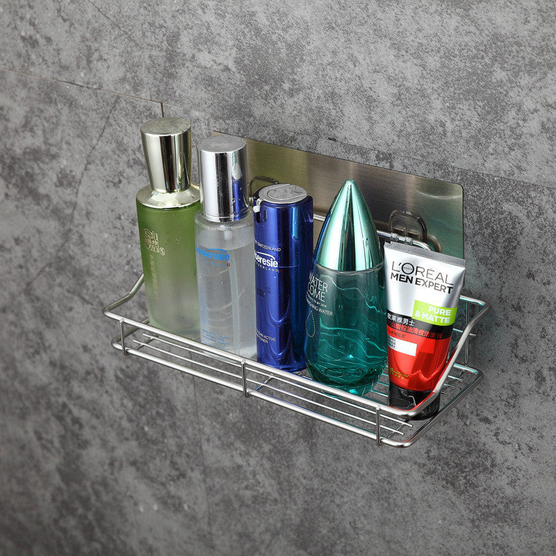 Metal wall-mounted shower caddy with various bathroom bottles on a gray concrete background
