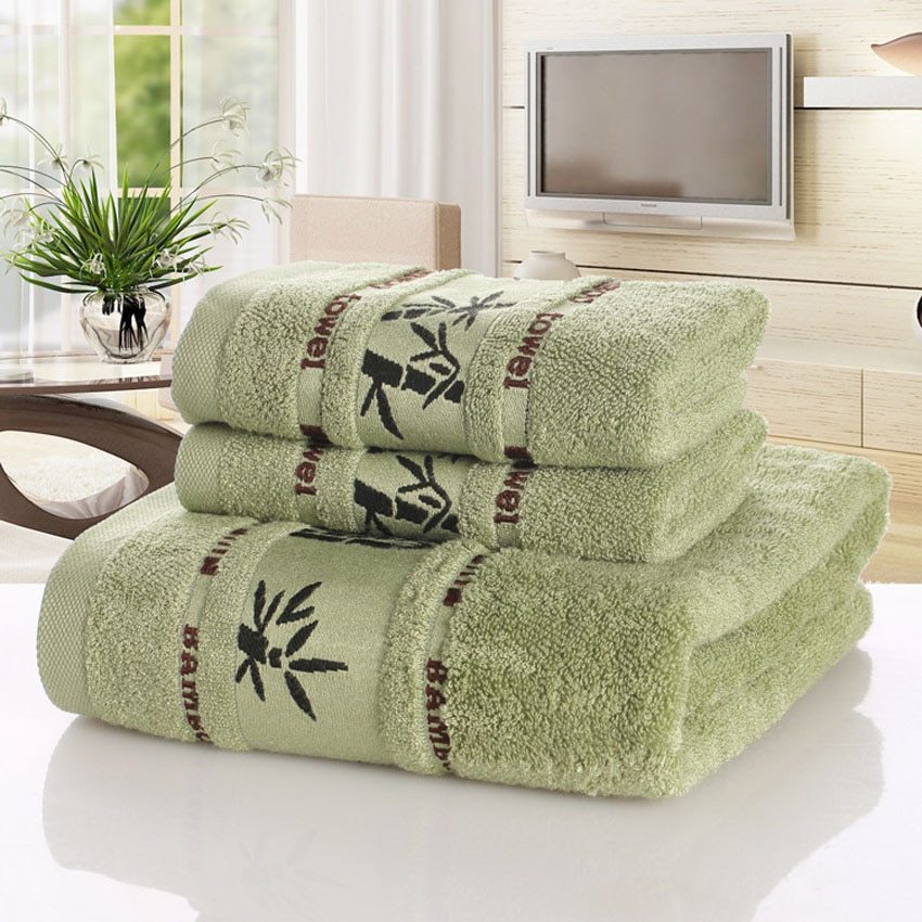 Stack of towels in yellow, green, and white with a bamboo style logo on a light background.