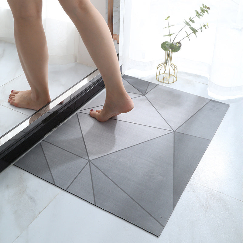 Person stepping onto a geometric-patterned bath mat in a bathroom setting.