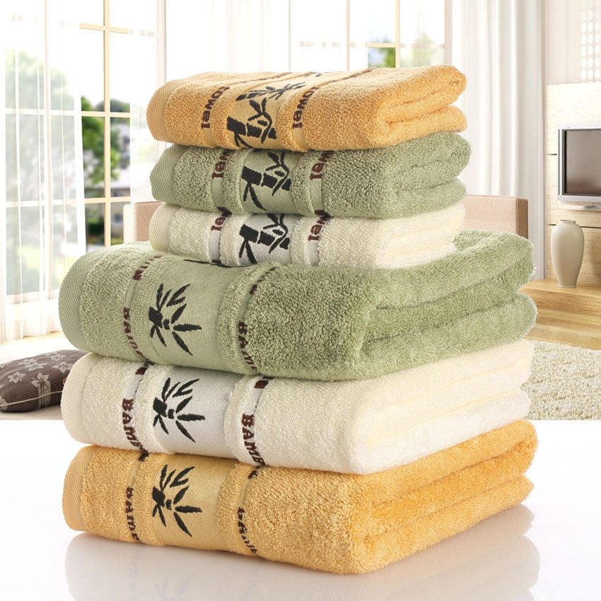 Stack of towels in yellow, green, and white with a bamboo style logo on a light background.