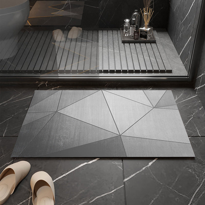 Person stepping onto a geometric-patterned bath mat in a bathroom setting.