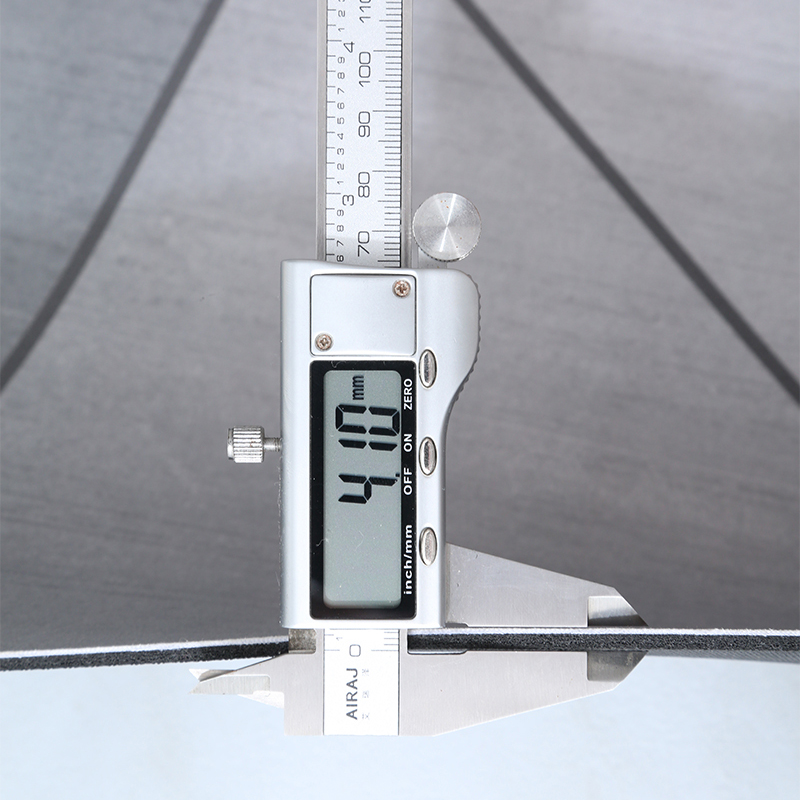 Digital vernier caliper measuring a bathmat's thickness with a clear background